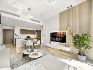 Ein modernes Wohnzimmer mit Flachbildfernseher, Essbereich und einer Küche im Hintergrund.