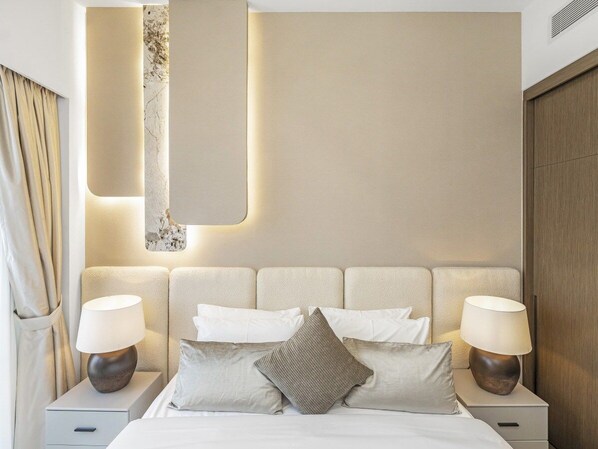 A hotel room with a bed, two bedside tables, and a headboard with integrated lighting.