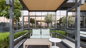 An outdoor seating area with a sofa and a small table, surrounded by a metal railing and glass panels. - New 1BR | Burj Khalifa Infinity Pool | Dubai Mall (Dubai)
