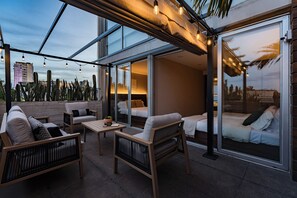 A modern outdoor patio with seating, a table, and a glass door leading to a bedroom. - Condesa Amazing 3BrApt W/PrivateTerrace/Pool 6 PAX (Ciudad de México)