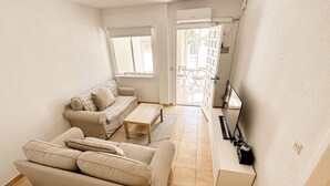 Una sala pequeña con sofá, una mesita de centro y un mueble para televisor.
