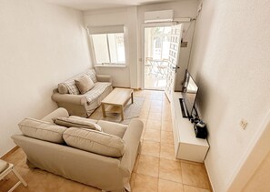 Uma sala de estar pequena com um sofá, uma mesa de centro e um rack para TV.