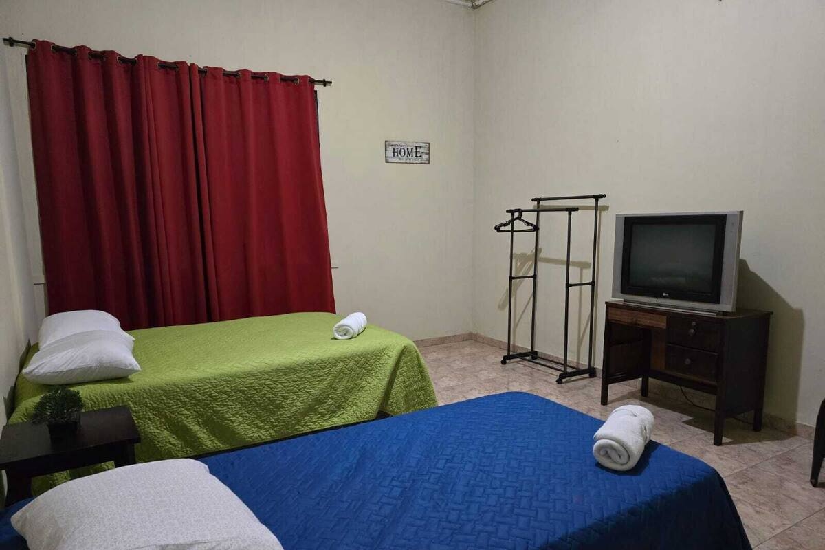 A room with two beds, a TV, and a coat rack.