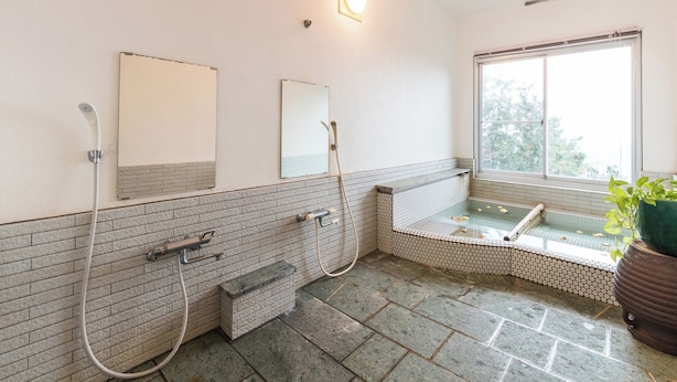 A bathroom with a bathtub, two sinks, a window, and a potted plant. - Villa FUN Kawana (Ito)