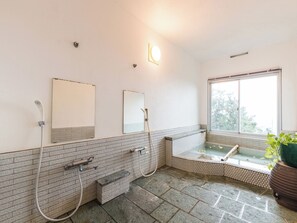 A bathroom with a bathtub, two sinks, a window, and a potted plant.
