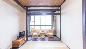 A traditional Japanese room with tatami flooring, a low wooden ceiling, and a television on a wooden stand. - Villa FUN Kawana (Ito)