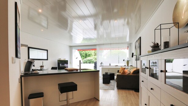 A modern kitchen with a central island, bar stools, and a view of the outdoors.
