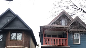 A two-story house with a blue exterior, a red front porch, and a balcony. - Large Charcter Home  (Moose Jaw)