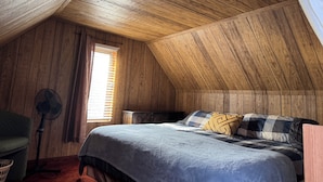 A cozy attic bedroom with wooden walls and a sloped ceiling. - Large Charcter Home  (Moose Jaw)
