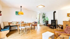 A spacious living area with a dining table, chairs, a sofa, a fireplace, and a hanging light fixture. - La Canonica Centovalli with Balconies and Garden, Camedo, Switzerland (Camedo)