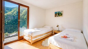 A bedroom with two beds, a balcony, and a painting on the wall. - La Canonica Centovalli with Balconies and Garden, Camedo, Switzerland (Camedo)