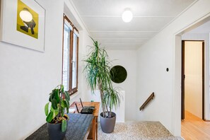 A hallway with a wooden floor, a potted plant, a framed picture, and a door. - La Canonica Centovalli with Balconies and Garden, Camedo, Switzerland (Camedo)