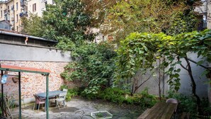 A courtyard with a table and chairs, a brick wall, and a wooden bench. - Gorki 11 Modern Escape (Milano)