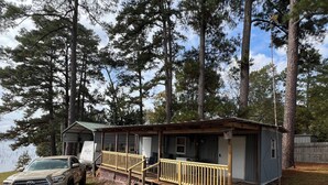 A cabin with a wooden deck, a truck, and a boat docked outside.