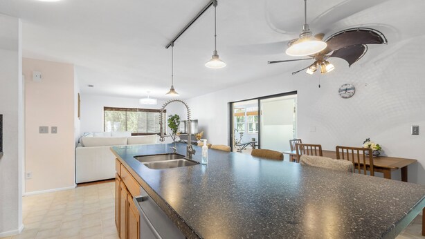A modern kitchen with a large island, pendant lights, and a ceiling fan.