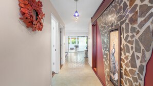 A hallway with a stone wall, a framed artwork, and a decorative wreath on the wall.