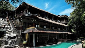 Ein mehrstöckiges Gebäude mit Pool, Steintreppe und einem Strohdach.