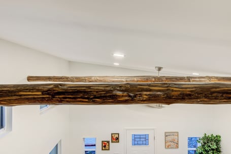 A room with a large wooden beam ceiling, white walls, a door with a window, and artwork on the walls.. Sleeps 5-6 Near RRG-Hot Tub-Nice Sunrise-Quiet