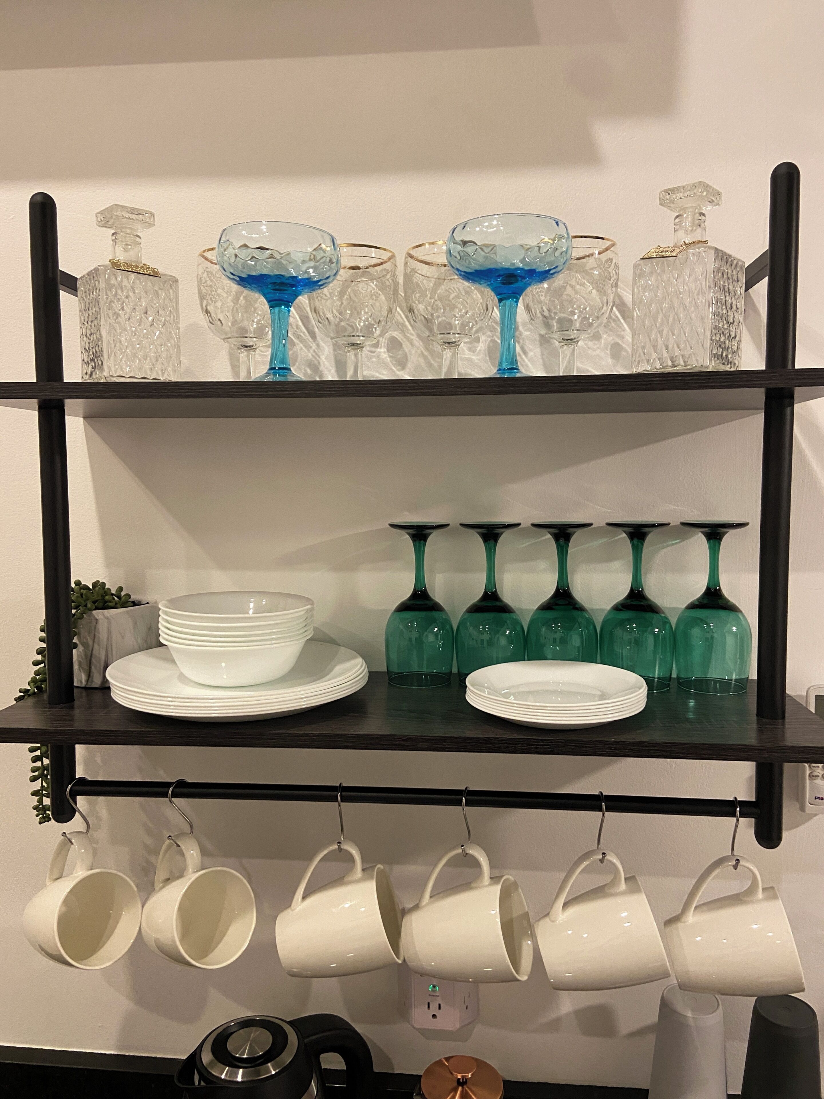 A shelf with various glassware and white mugs.