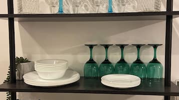 Une étagère avec divers objets en verre et des tasses blanches.