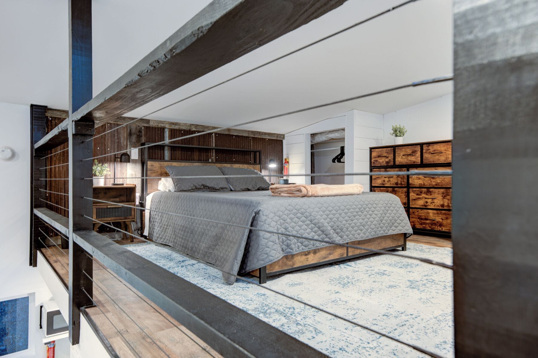 A modern bedroom with a bed, wooden storage, and a view of the outdoors.