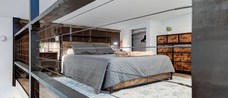Un dormitorio moderno con cama, almacenaje de madera y vistas al exterior.