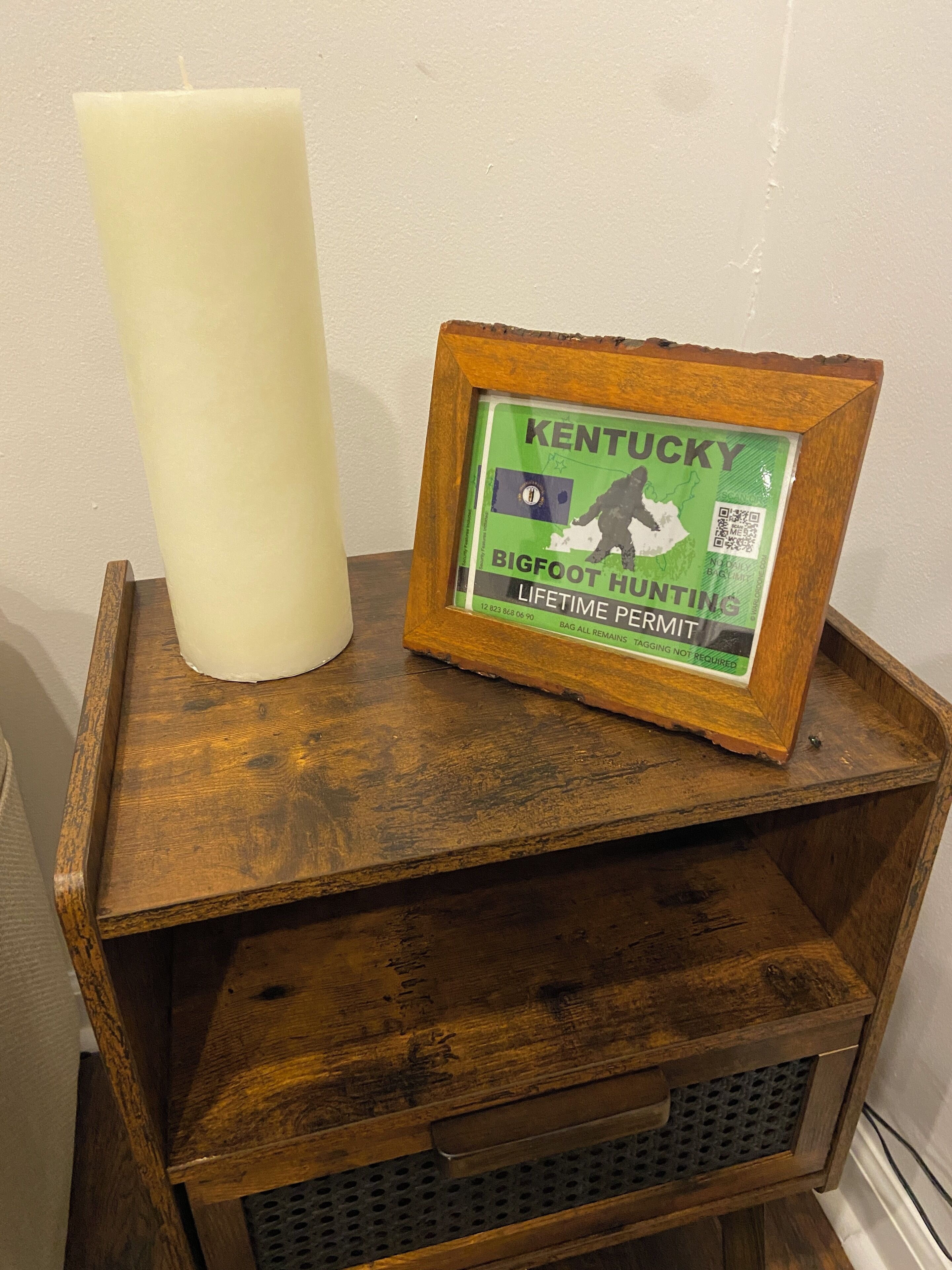 Een houten plank met een lijst en een witte kaars.