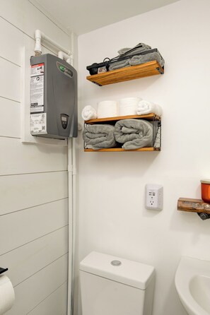 A bathroom with a toilet, a sink, a towel rack, and a heater.
