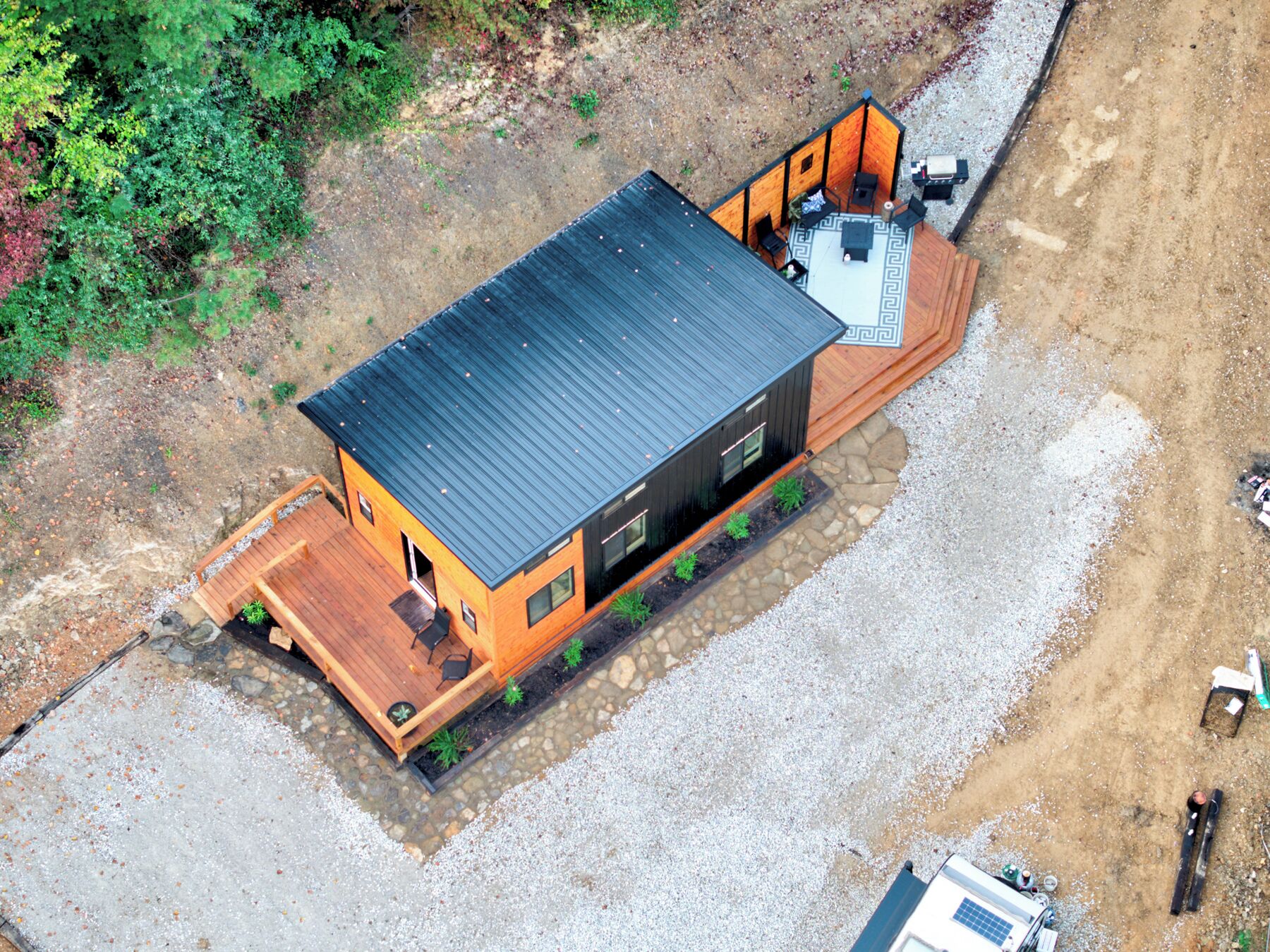Una casa moderna a due piani con una terrazza in legno e un tetto in metallo nero.