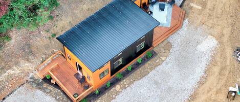 Una casa moderna a due piani con una terrazza in legno e un tetto in metallo nero.