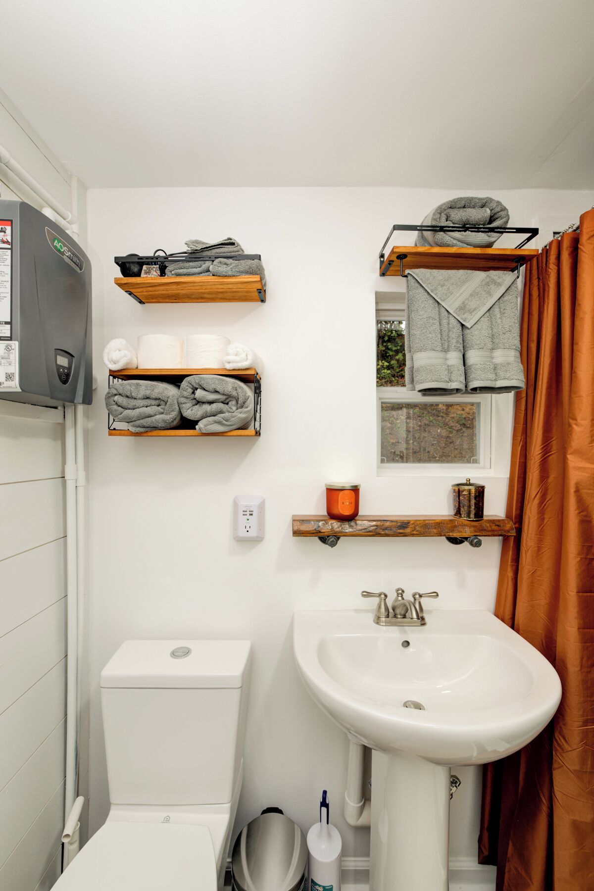 Une salle de bain équipée de toilettes, d’un lavabo, de porte-serviettes et d’un radiateur.