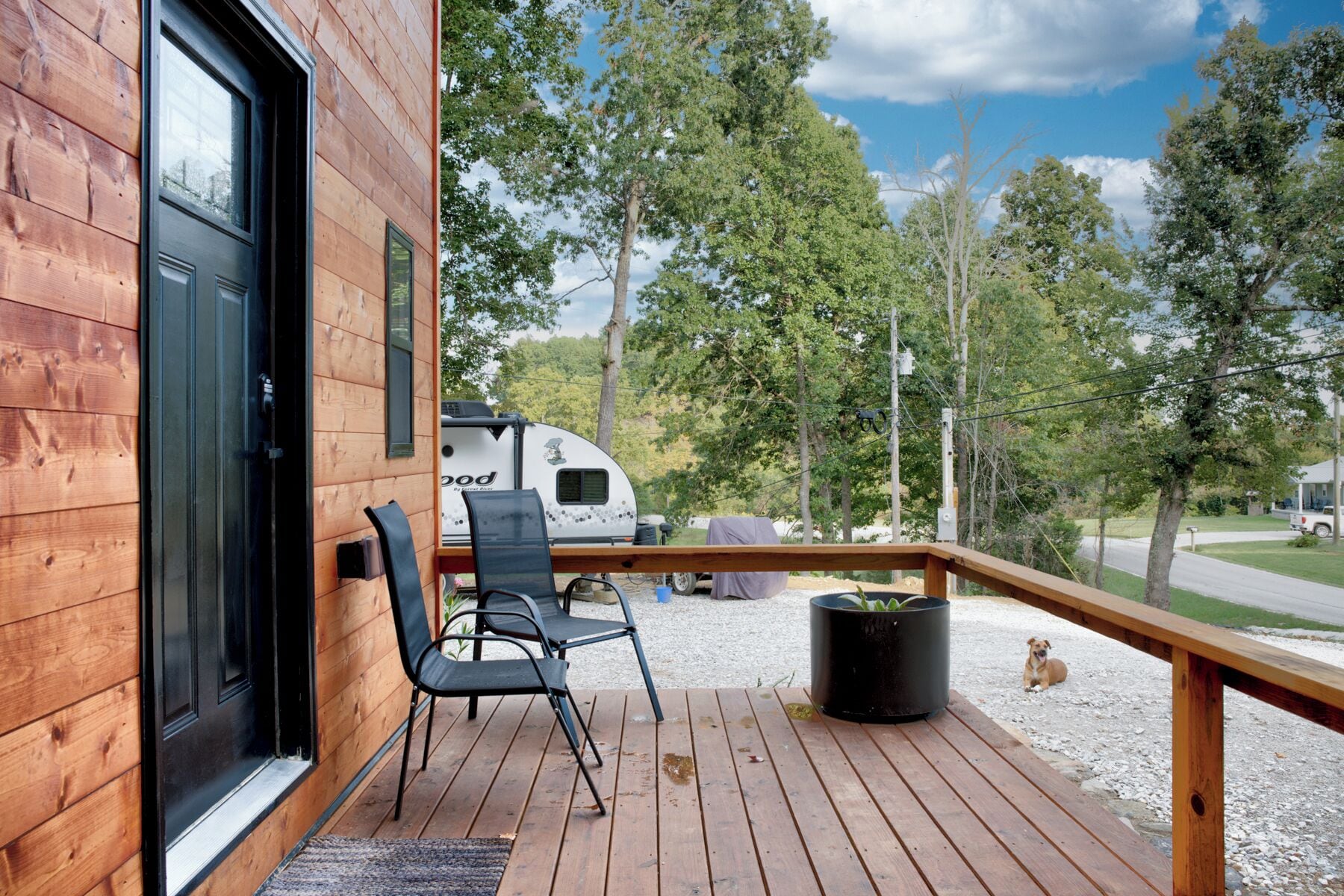 A wooden deck with a seating area, a black chair, and a potted plant.