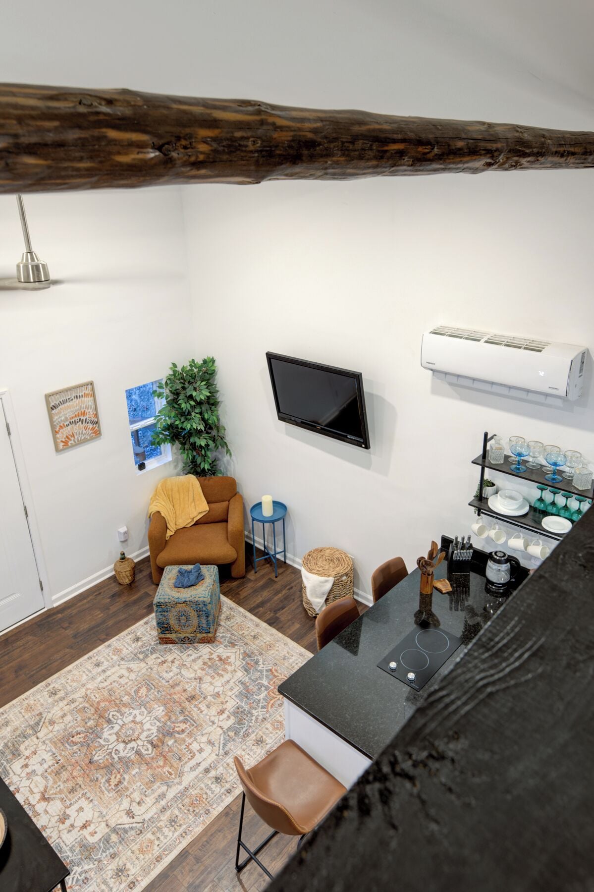 A modern living room with a flat-screen TV, a sofa, a coffee table, and a kitchen area with a countertop and sink.