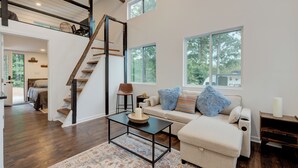 A spacious living room with a high ceiling, a staircase, and large windows offering views of the outdoors. - Sleeps 5-6 Near RRG-Hot Tub-Nice Sunrise-Quiet (Beattyville)