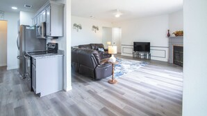 Et moderne køkken med stålemfangere og en opholdsstue med en lædersofa og et fjernsyn.