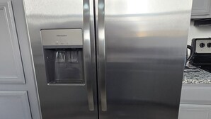 Et køleskab i rustfrit stål med vanddispenser, dobbelt døre og et fryserum.