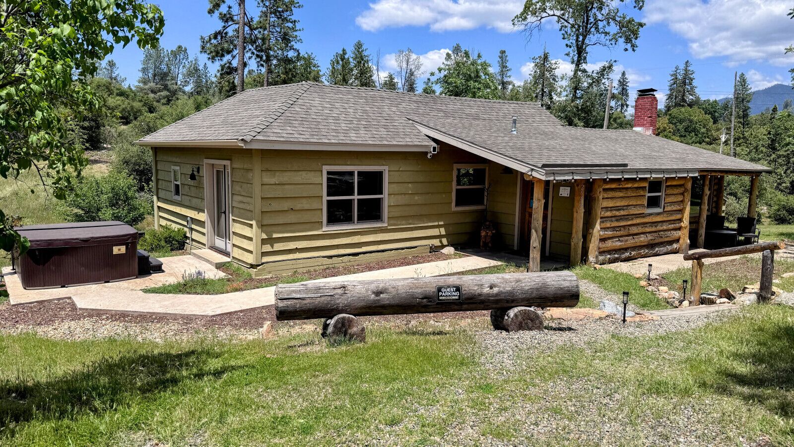 Un chalet rustique en rondins de bois, doté d’une cheminée, d’un espace de stationnement pour les invités et d’un bain à remous.