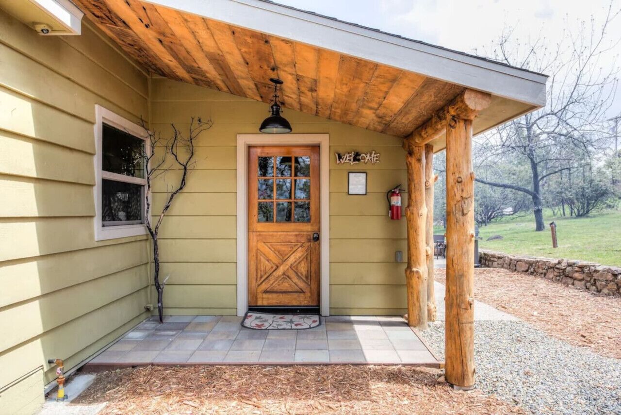 A wooden porch with a door, a fire extinguisher, and a welcome sign.