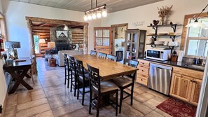 Una cocina amplia con una gran mesa de madera y sillas, estufa integrada y microondas.