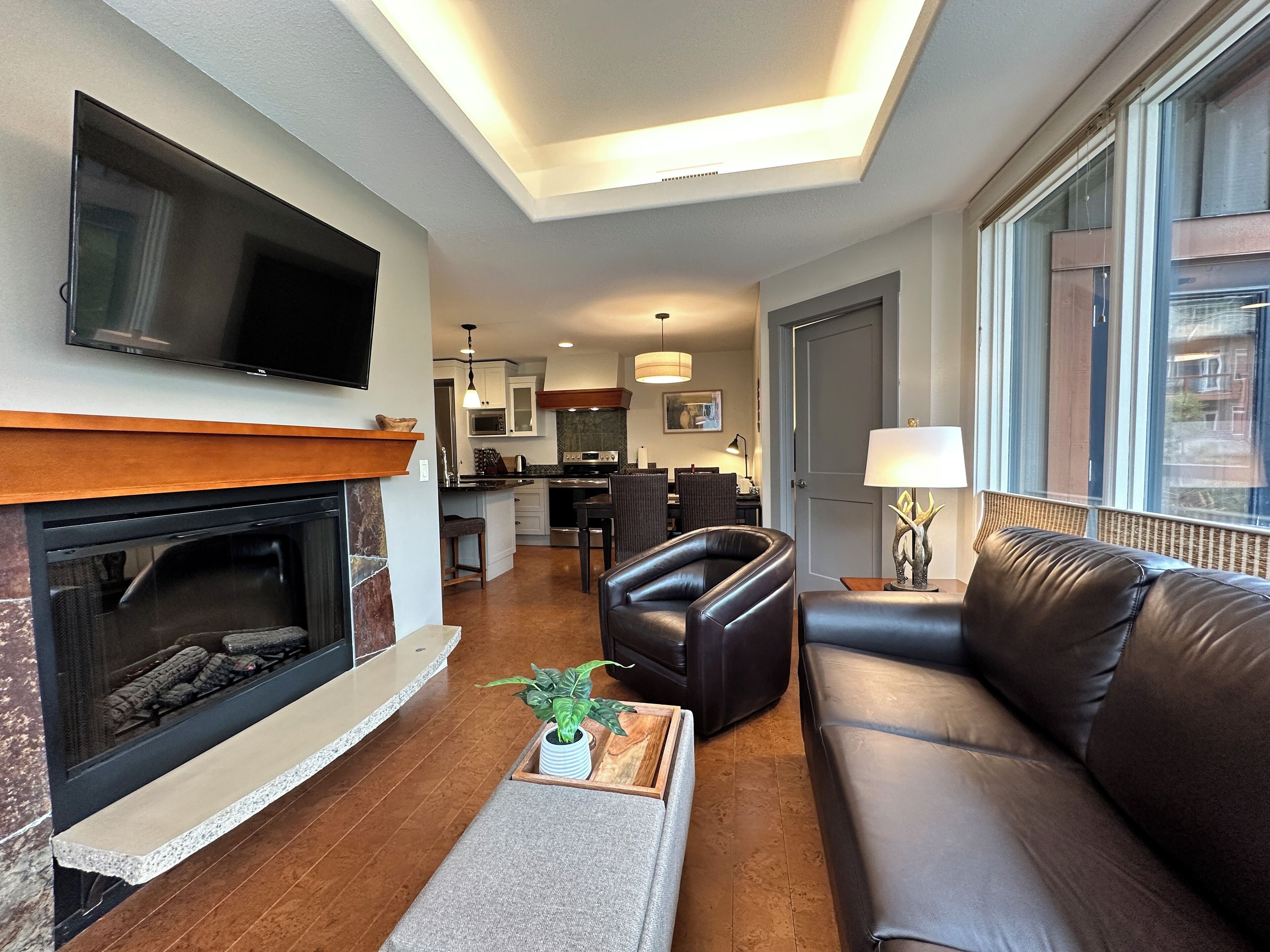 A modern living room with a fireplace, leather sofa, and a television mounted on the wall.