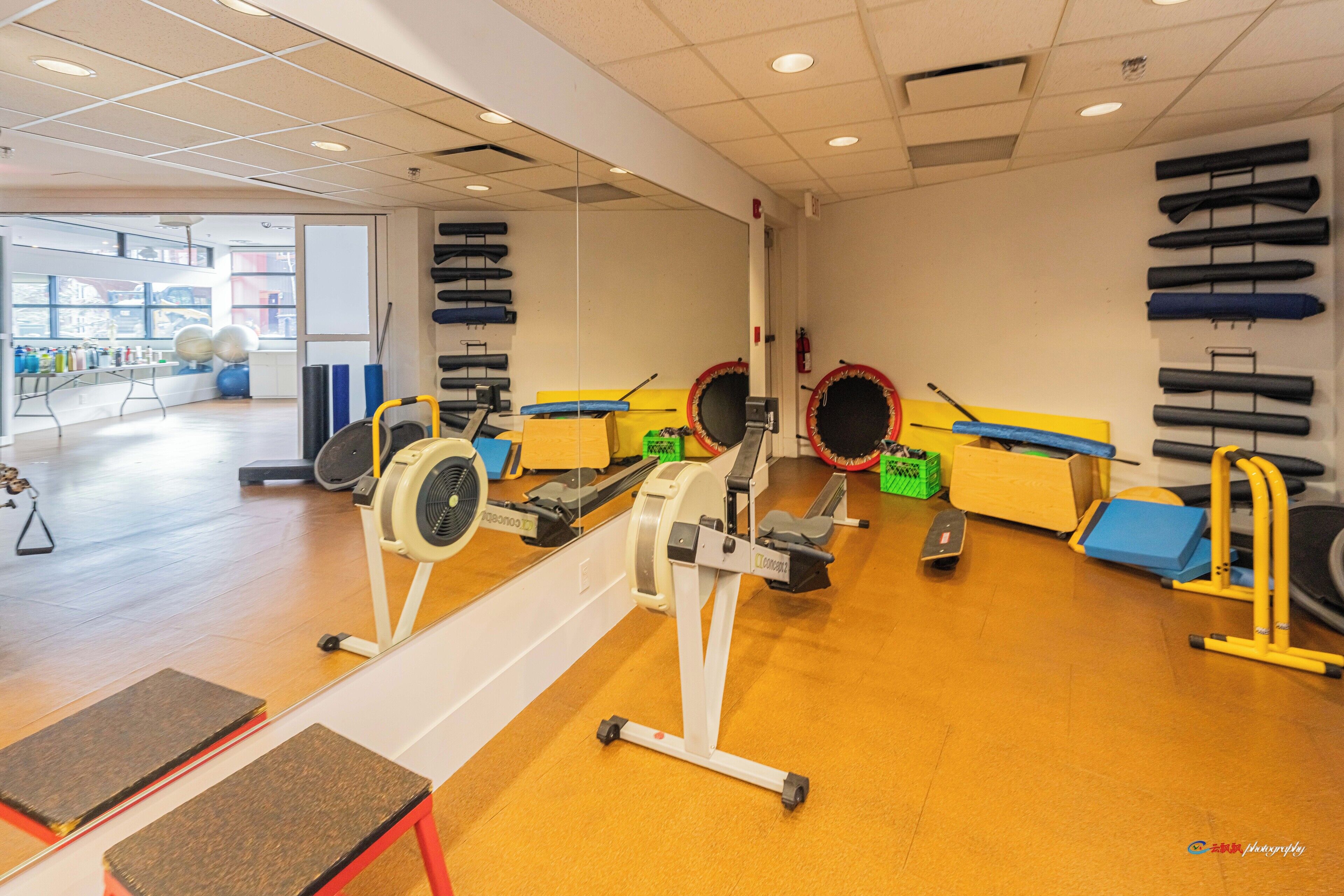 Un gimnasio con máquinas de cardio, equipo de levantamiento de pesas y un muro de espejos.