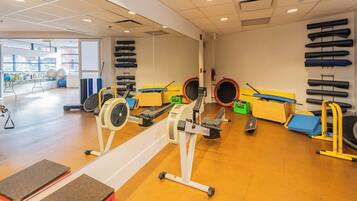 Un gimnasio con máquinas de cardio, equipo de levantamiento de pesas y un muro de espejos.