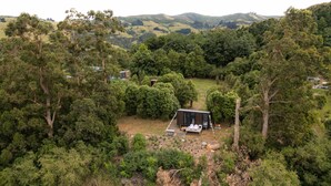 A secluded cabin surrounded by dense forest, with a small deck and outdoor seating area.