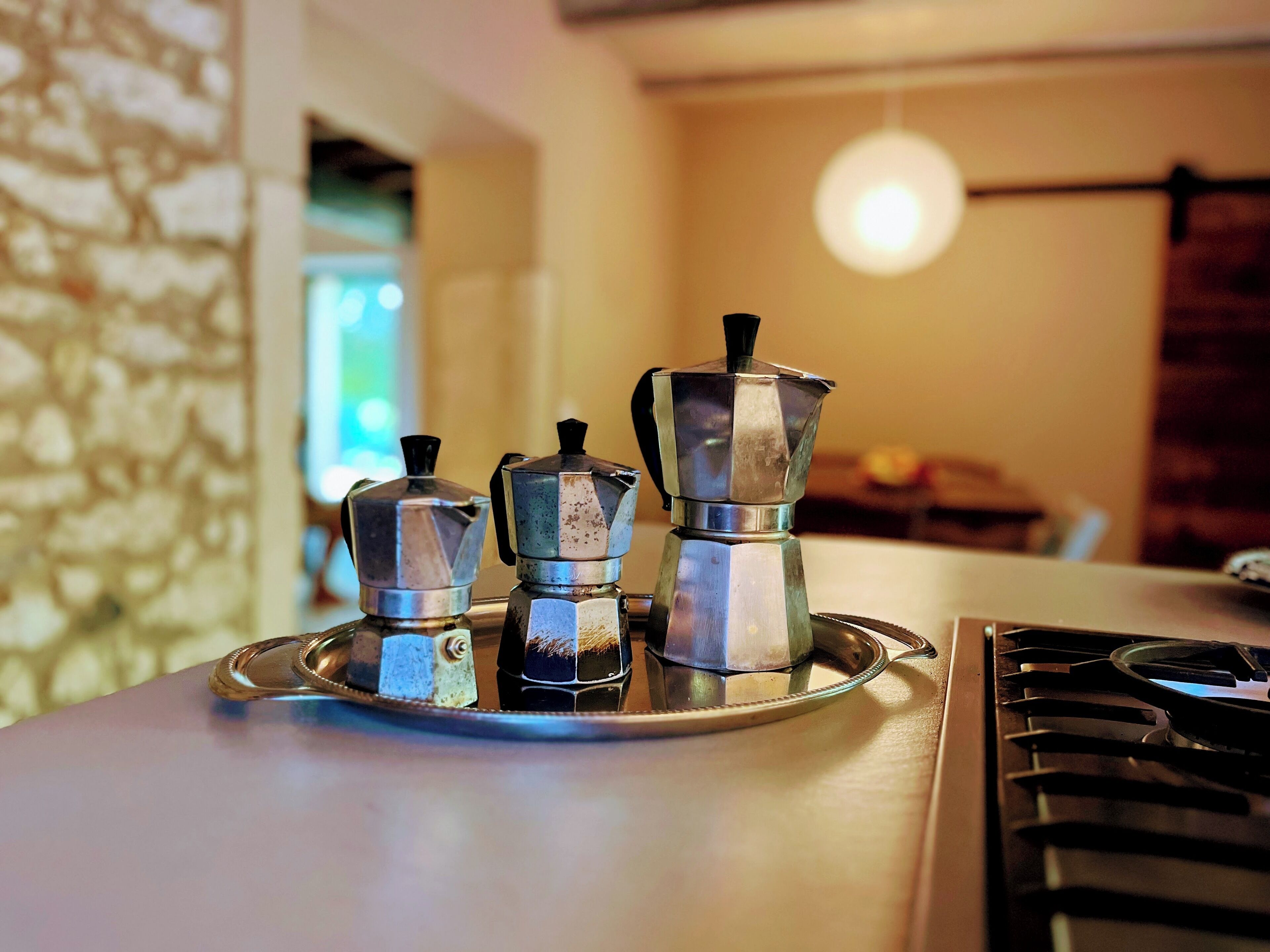 A kitchen counter with three coffee makers on a tray.
