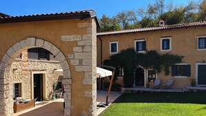 A traditional stone building with an arched entrance, a patio with outdoor seating, and a well-maintained lawn.