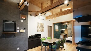 A modern kitchen with a dining area, wooden beams, and a large TV. - HOTEL SOBOKU (Myoko)