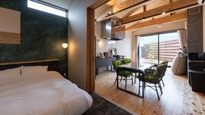 A modern hotel room with a large bed, a dining area with a table and chairs, and a view of the outdoors. - HOTEL SOBOKU (Myoko)