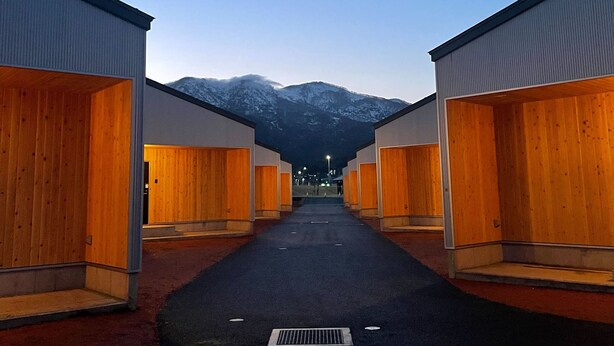 A row of cabins with wooden doors and metal exteriors, set against a mountain backdrop. - HOTEL SOBOKU (Myoko)
