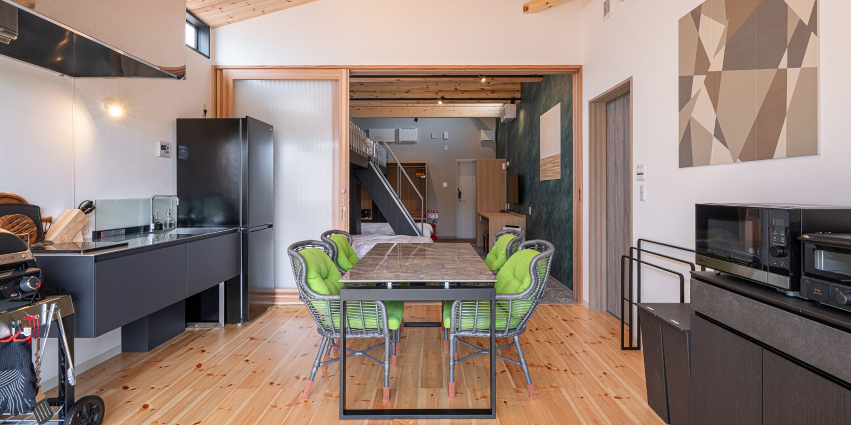 A modern kitchen with a dining area, featuring a large island, chairs, and a microwave.