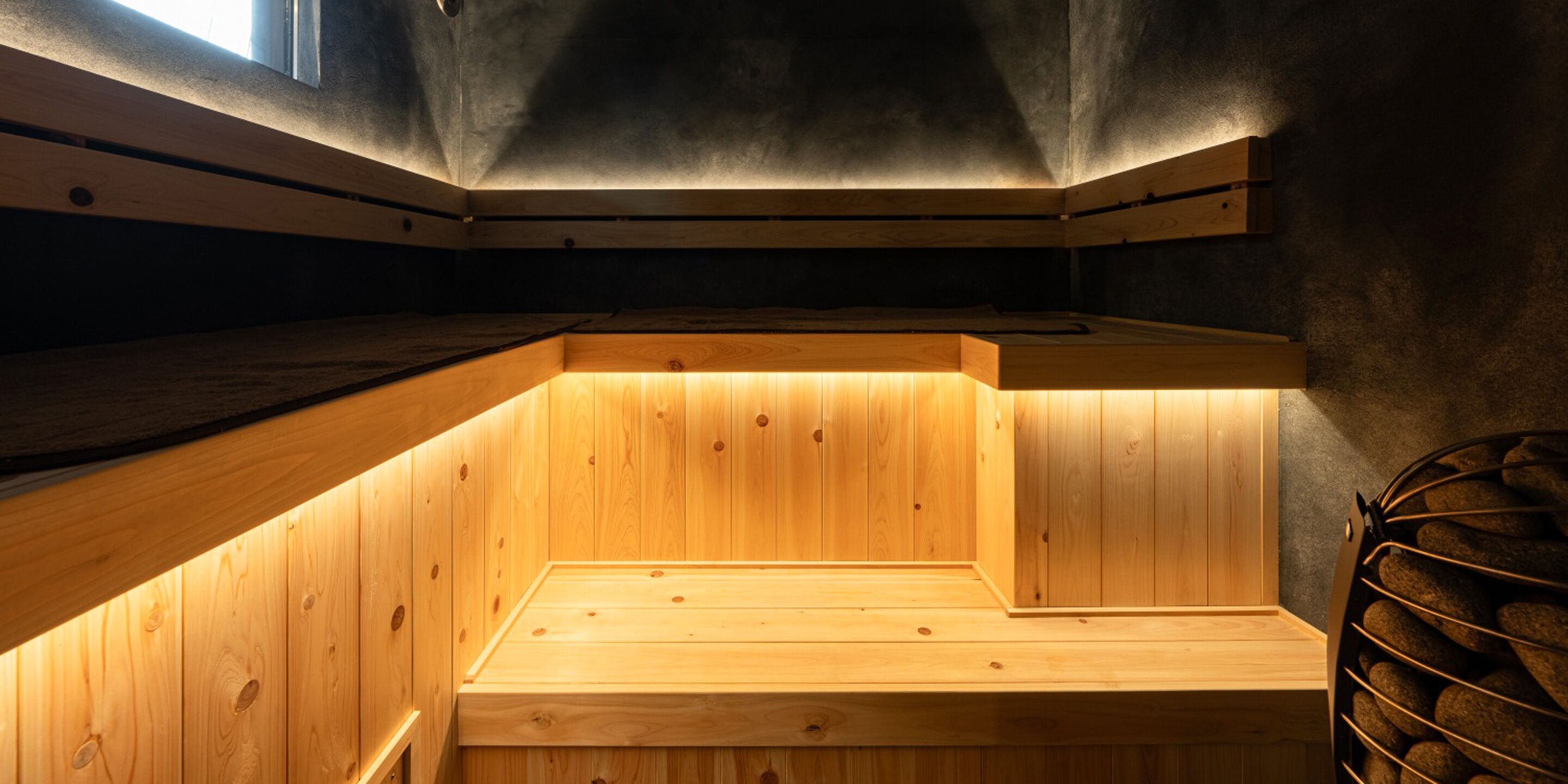A sauna with wooden benches and a stone shelf.
